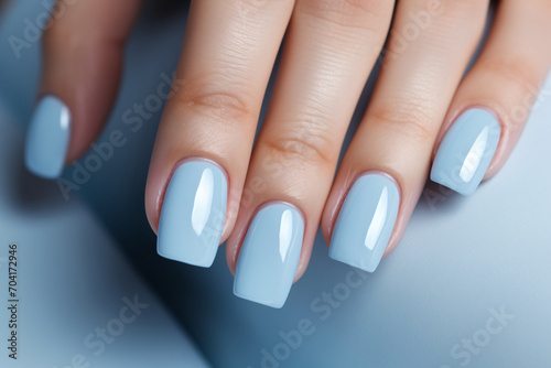 Glamour woman hand with baby blue nail polish on her fingernails. Blue nail manicure with gel polish at luxury beauty salon. Nail art and design. Female hand model. French manicure.