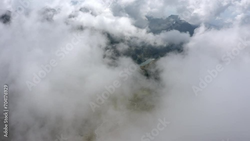 Aerial Idyllic Shot Of Lake On Tranquil Rock Formation, Drone Flying Forward In Clouds - French Alps, France photo