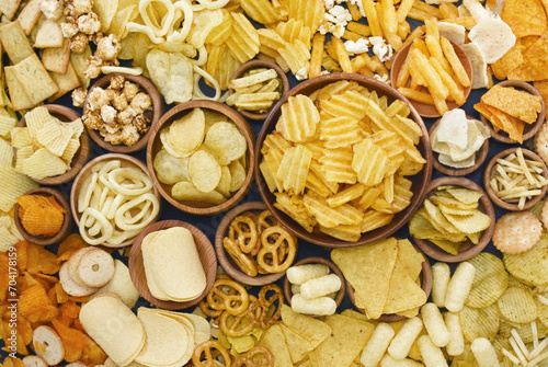 Colorful mix of salty snacks for beer varieties: chips and pretzels, onion rings and crackers. Non-healthy junk food background