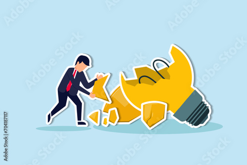Uninspired or motivation after business failure, burnout or exhausted from crisis, no new idea or inspiration concept, depressed business man sadly standing with fail old broken lightbulb idea.