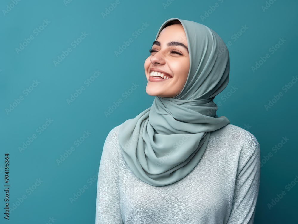 Muslim woman smiling looking up isolated on blue background Muslim woman smiling looking up isolated on blue background