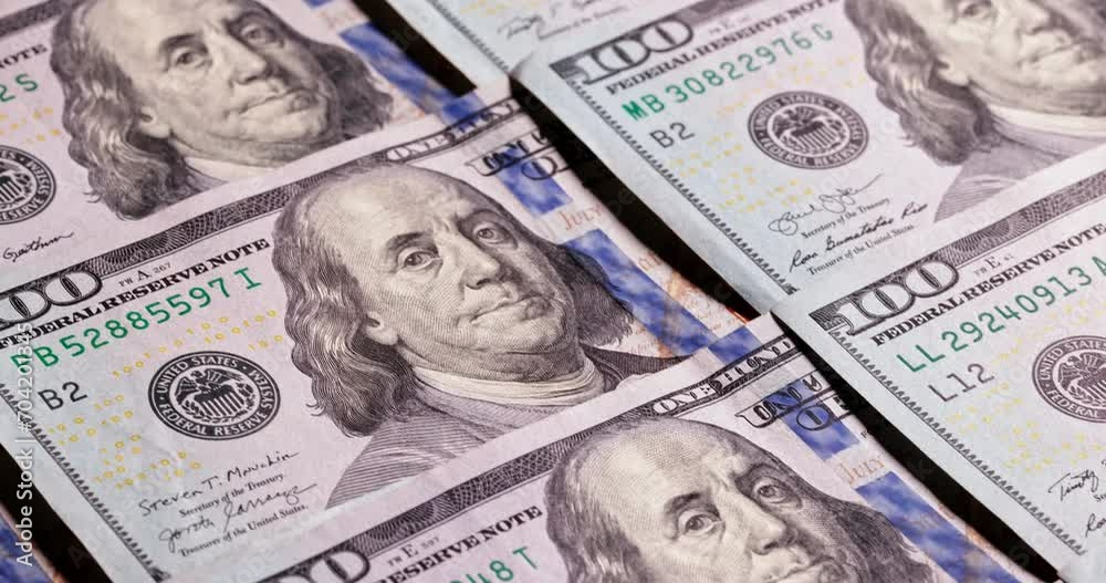 Smooth movement over neatly laid out hundred dollar bills. Cash banknotes with portrait of Benjamin Franklin. American dollars for finance and investment concept. Rich US business economy, copy space Smooth movement over neatly laid out hundred dollar bills. Cash banknotes with portrait of Benjamin Franklin. American dollars for finance and investment concept. Rich US business economy, copy space