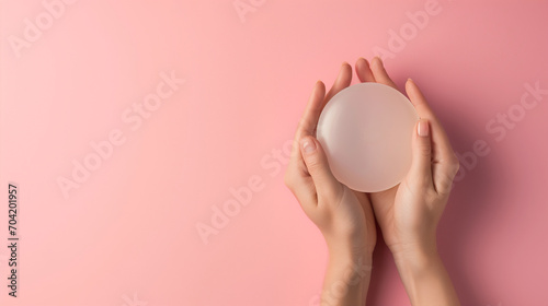 woman Holding a Translucent silicone Over Pink Background, concept for breast augmentation.