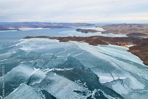 Frozen Lake Baikal. Cloudy stormy sky  clear ice in the cracks. Winter landscape from the air.
