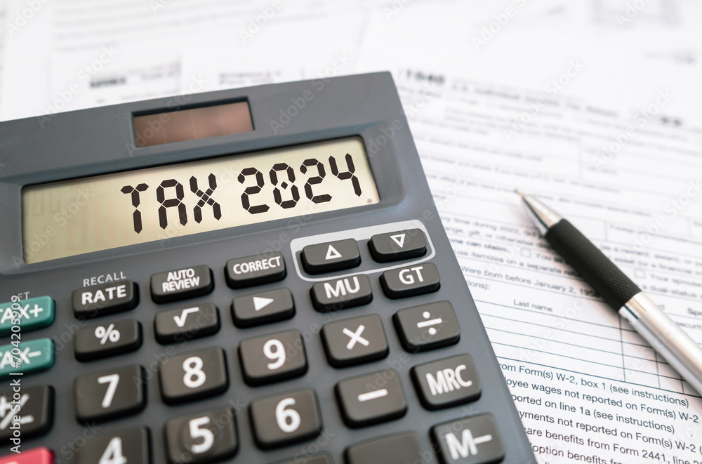 Word TAX 2024 on the calculator and personal income tax form. Business and tax concept. Word TAX 2024 on the calculator and personal income tax form. Business and tax concept.