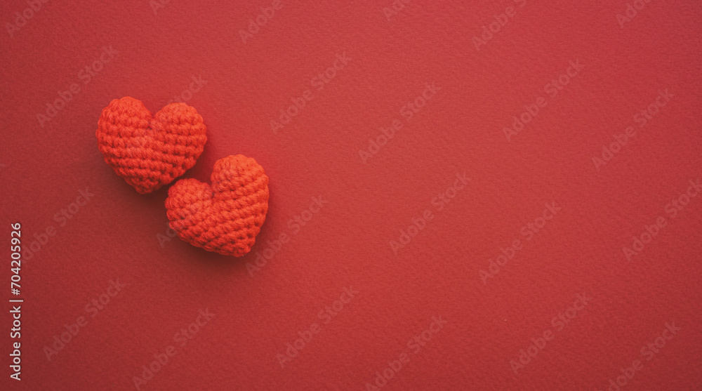 Two red hearts are placed on dark red paper with copy space. Love and Valentines day concept