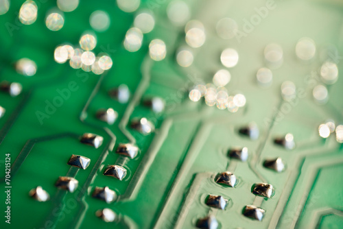 Conductor traces with silver drops of solder on a green electronic circuit. Computer board with electrically conductive circuits of an electronic circuit in the form of stripes in a blur. photo