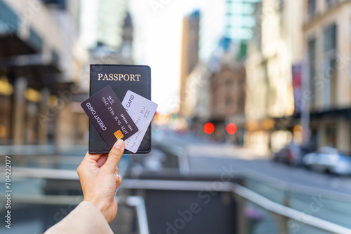 Asian woman hand holding credit card and passport in the city. Attractive girl enjoy outdoor lifestyle travel in Sydney on holiday vacation. Cashless payment and international transportation concept.