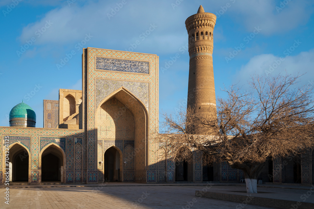 The main entrance and courtyard of the Kalyan Mosque - the main Friday mosque of Bukhara and the Kalyan Minaret in the background on a sunny day, Bukhara, Uzbekistan
