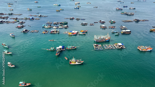 Aerial view of a busy aquaculture farm and fishing boats clustered in a calm, blue sea