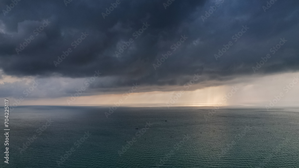 A vast ocean under a dramatic cloudy sky with sunlight piercing through, symbolizing tranquility and the power of nature