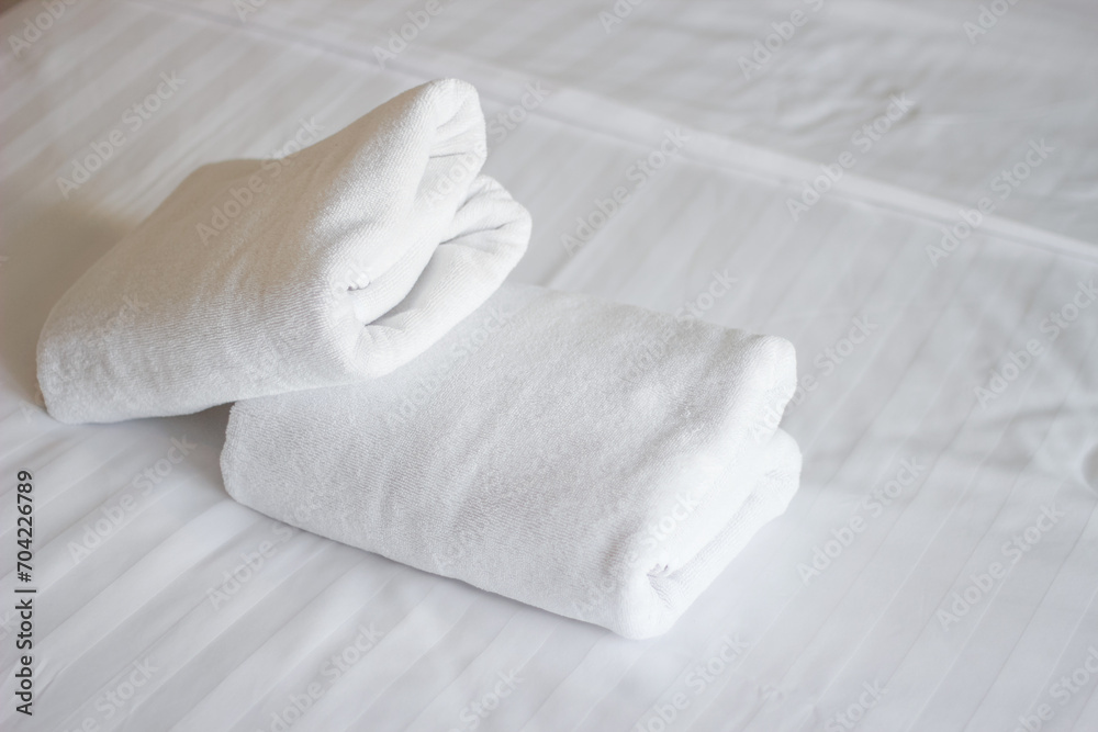 Fototapeta premium Stack of white towels on bed in hotel