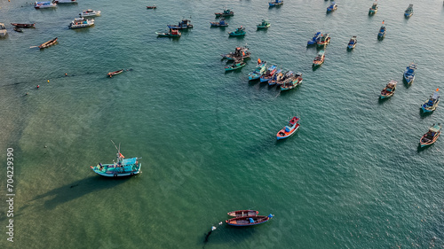 Aerial view of numerous colorful fishing boats scattered across a calm, turquoise sea, depicting a bustling coastal fishing industry photo