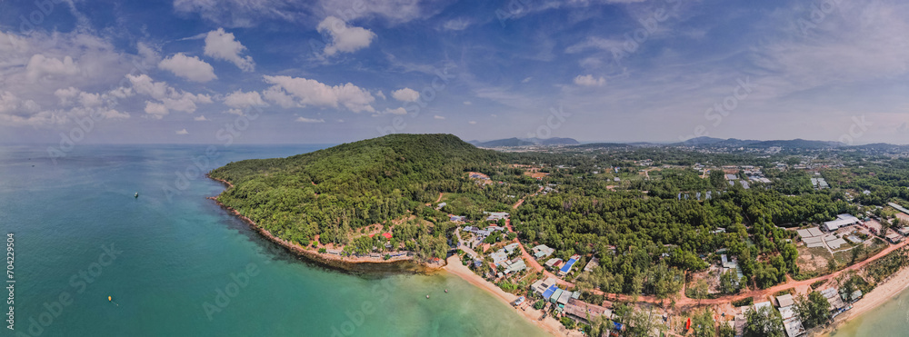 Panoramic aerial view of a lush tropical peninsula with clear blue waters, sandy beaches, and scattered settlements
