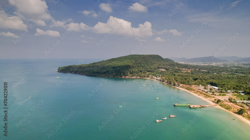 Aerial view of a tranquil tropical coastline with lush greenery and boats dotting the calm turquoise waters, ideal for travel or vacation concepts