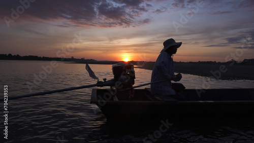 Silhouette of a fishermen on boat with outboard motor boat ready to fishing during beautiful sunrise.