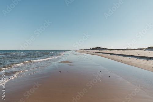 vue sur une longue plage avec le mouvement des vagues avec personne à l'horizon en été lors d'une journée ensoleillée