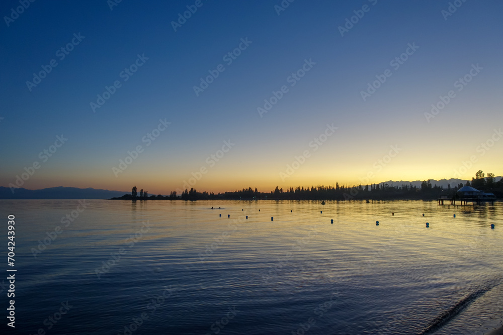 Colorful sunset on the sea. Mountain lake in the rays of the orange sun. Kyrgyzstan, Lake Issyk-Kul. natural background