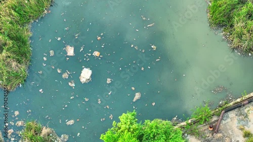Dirty factory water dumped into rivers hurts fish and plants, messing up nature big time. Chemical Contaminants and sewage pollution concept. Bird's eye view by drone. Stock footage.
 photo