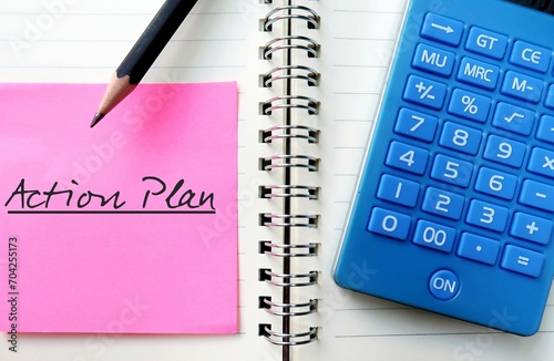 Pink paper note on notebook with pencil writing ACTION PLAN, to write proposed strategy or course of action,  lists what steps must be taken in order to achieve specific goal photo