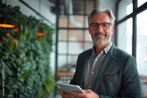 Smiling middle aged business man ceo investor using tablet computer, mature older businessman executive looking at camera advertising finance trading work standing in office. Generative AI  photo