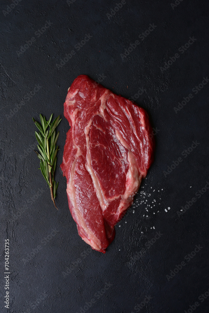 Raw organic marbled beef steak with ingredients for cooking. Top view with copy space.
