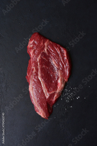 Raw organic marbled beef steak with ingredients for cooking. Top view with copy space.