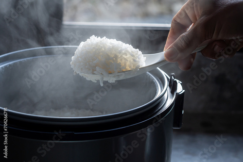 Jasmine rice cooking in electric rice cooker with steam on dark background. Soft Focus,