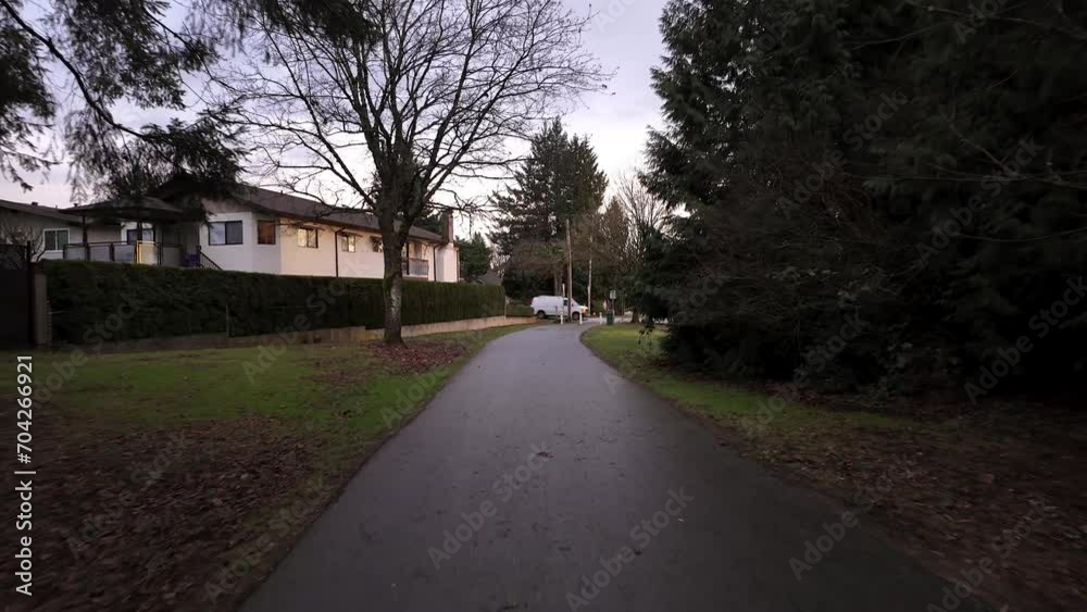 Suburban Neighborhood Path surrounded by trees and homes during sunny sunset. Rainy, Winter Season. Burnaby, Vancouver BC Canada. Suburban Neighborhood Path surrounded by trees and homes during sunny sunset. Rainy, Winter Season. Burnaby, Vancouver BC Canada.