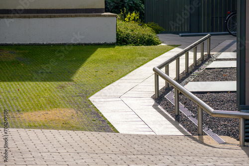 A cobblestone pedestrian path with manicured green grass and small decorative stones © Jorens