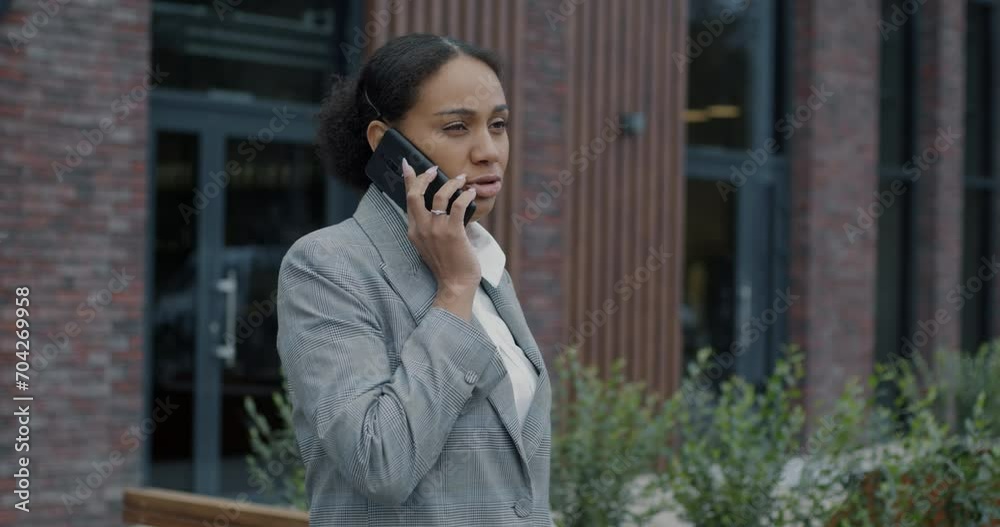 African American businesswoman speaking on mobile phone discussing work project standing in city street outdoors. Modern communication and people concept. African American businesswoman speaking on mobile phone discussing work project standing in city street outdoors. Modern communication and people concept.
