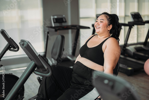 Plus size Asian woman exercises in gym. Beautiful overweight woman in sportswear doing cardio workout in fitness. concept of body positive, self-acceptance, weight loss.