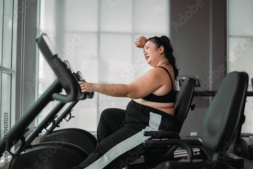 Plus size Asian woman exercises in gym. Beautiful overweight woman in sportswear doing cardio workout in fitness. concept of body positive, self-acceptance, weight loss.