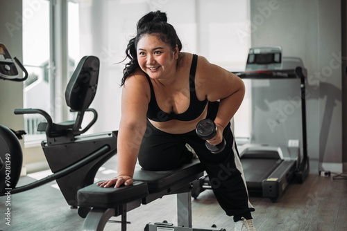 Plus size Asian woman exercises in gym. Beautiful overweight woman in sportswear doing workout in fitness. concept of body positive, self-acceptance, weight loss.