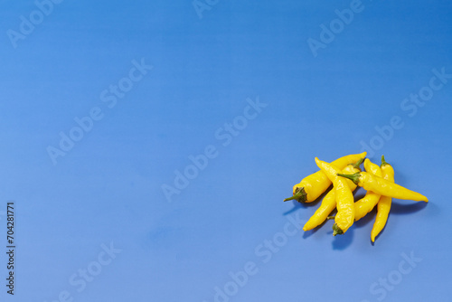 黄色系唐辛子を複数右下に複数配置した青色系背景あり俯瞰撮影