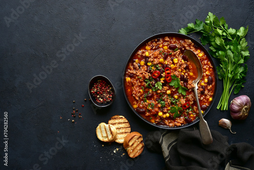 Chili con carne - traditional mexican minced meat and vegetables stew in tomato sauce in a cast iron pan . Top view with copy space. photo