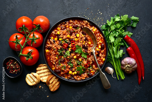 Chili con carne - traditional mexican minced meat and vegetables stew in tomato sauce in a cast iron pan . Top view with copy space. photo