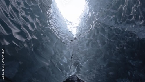 Walk through a majestic Ice Cave bridge of a melting glacier with a river  photo