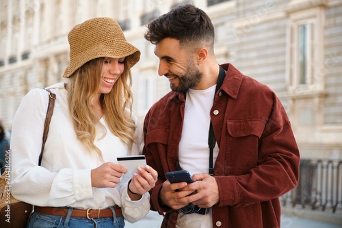 Young Caucasian couple buying the tour tickets with credit card and phone to visit Madrid, Spain.
