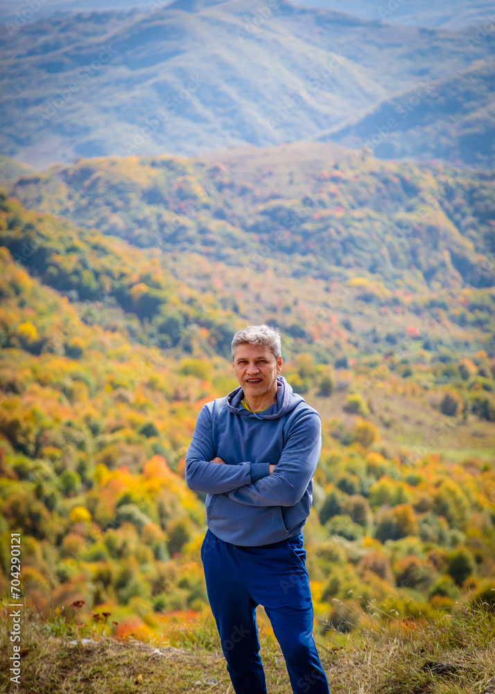 Adult man standing on the background of autumn mountains
