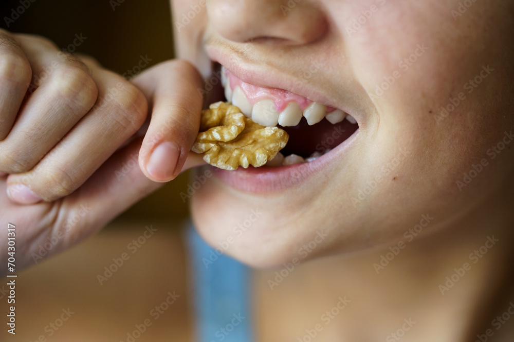 Crop unrecognizable teenage girl eating healthy walnut Crop unrecognizable teenage girl eating healthy walnut