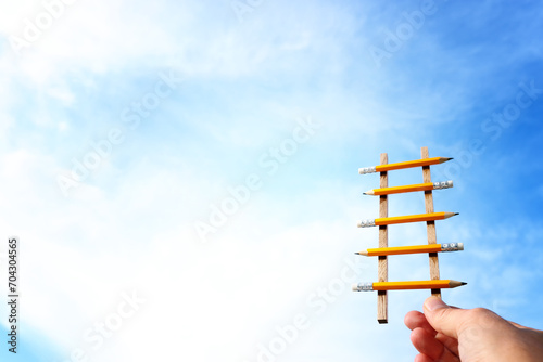 Concept image of a ladder made of pencils reaching the clouds. Idea of education  success and achieving goals