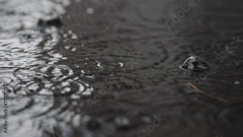 closeup of summer heavy rain drops falling into puddles on asphalt
