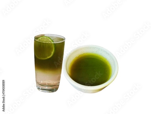 In the picture, there is a half cup of green tea in a small white cup. Nearby is green tea in a glass of lemon juice, decorated with a slice of lemon in the glass. It is fragrant and sour.