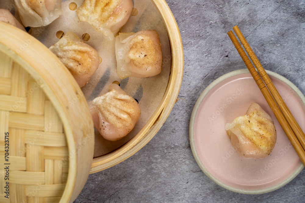 Homemade dumplings dim sum close-up in a bamboo steamer box on table. Horizontal top view from above