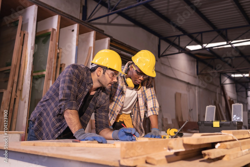 Young affrican american and white men carpenter labor, craftman working in wood workshop together, talking. Timber industry and furniture industry. © Wanwajee