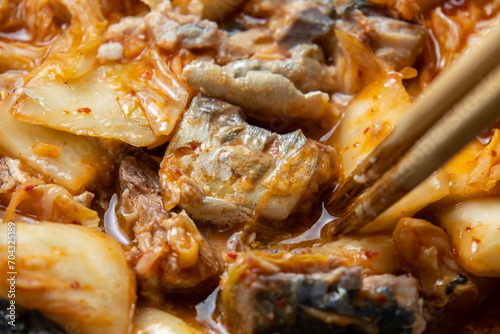 キムチと鯖水煮をフライパンで炒める調理シーン。 