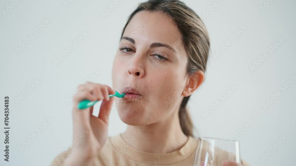 Video of pretty young woman brushing her teeth while looking at the mirror in the bathroom at home. Video of pretty young woman brushing her teeth while looking at the mirror in the bathroom at home.