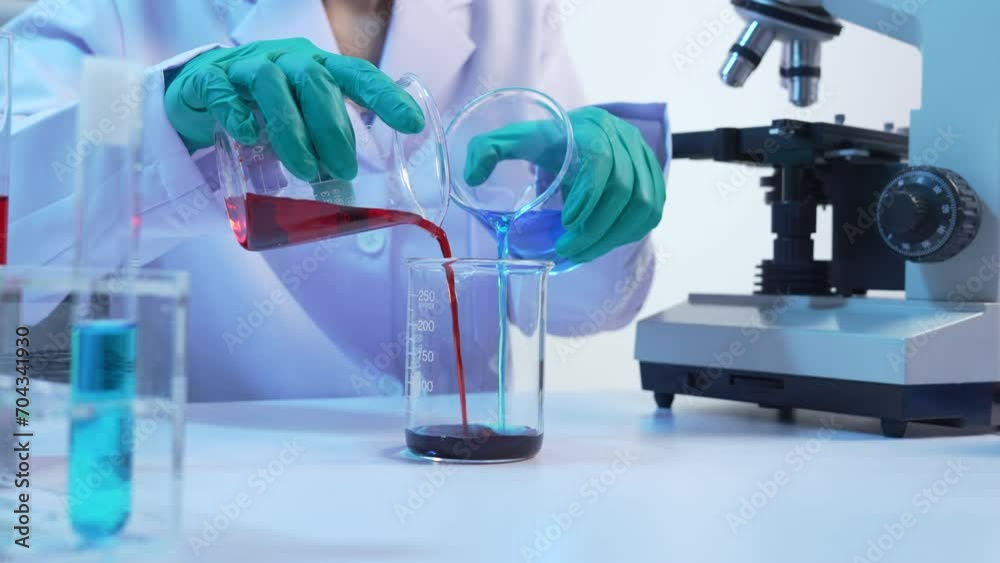 Asian people scientist in lab coat and protective gloves working with test tubes with mix liquids, with microscope and other test tubes in the background in laboratory.