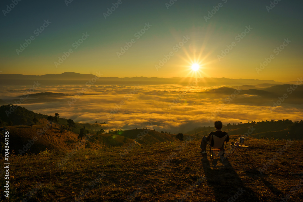 Fototapeta premium Asian Man is happy and relaxed with the scenery of the sea mist a beautiful natural in the morning at Car Camping site on the top of a mountain in winter season at Chiang Mai, Thailand.